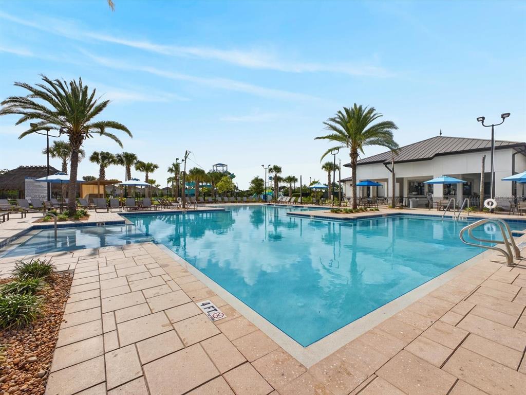 A large outdoor swimming pool with palm trees and a clubhouse under a blue sky — 967 SPLASH SHOT PLACE UNIT 2503, DAVENPORT, FL