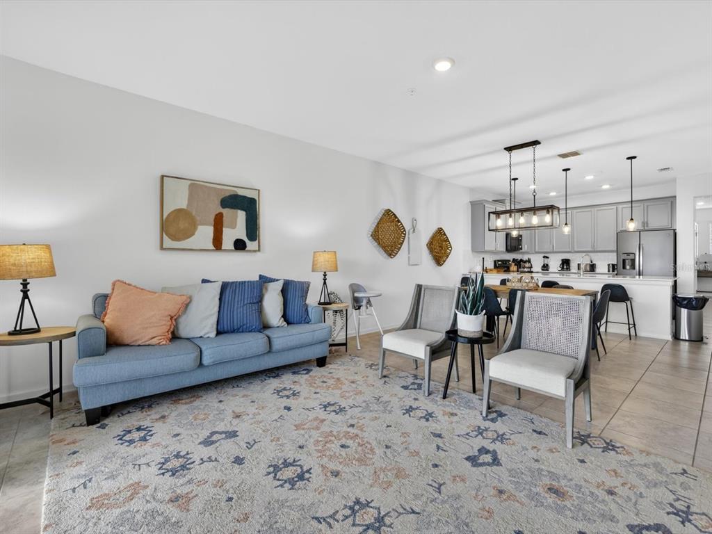A living room with a blue sofa and two chairs opens to a kitchen area — 967 SPLASH SHOT PLACE UNIT 2503, DAVENPORT, FL