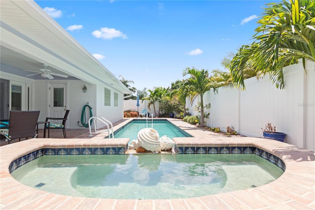 A backyard features a swimming pool and spa with brick coping and a white fence — 12352 83RD AVENUE, SEMINOLE, FL