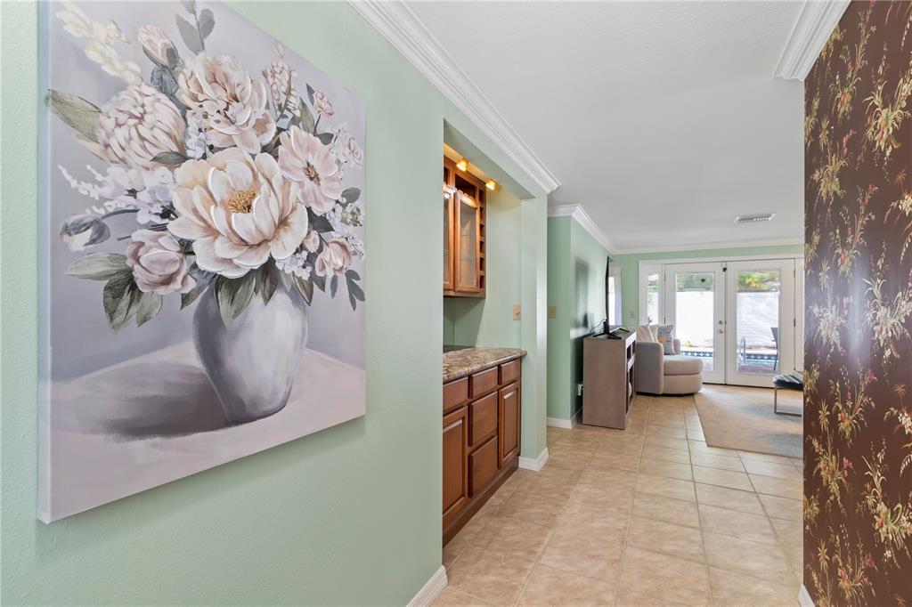 A hallway with a floral painting and wallpaper leads to a living area with tile floors — 12352 83RD AVENUE, SEMINOLE, FL