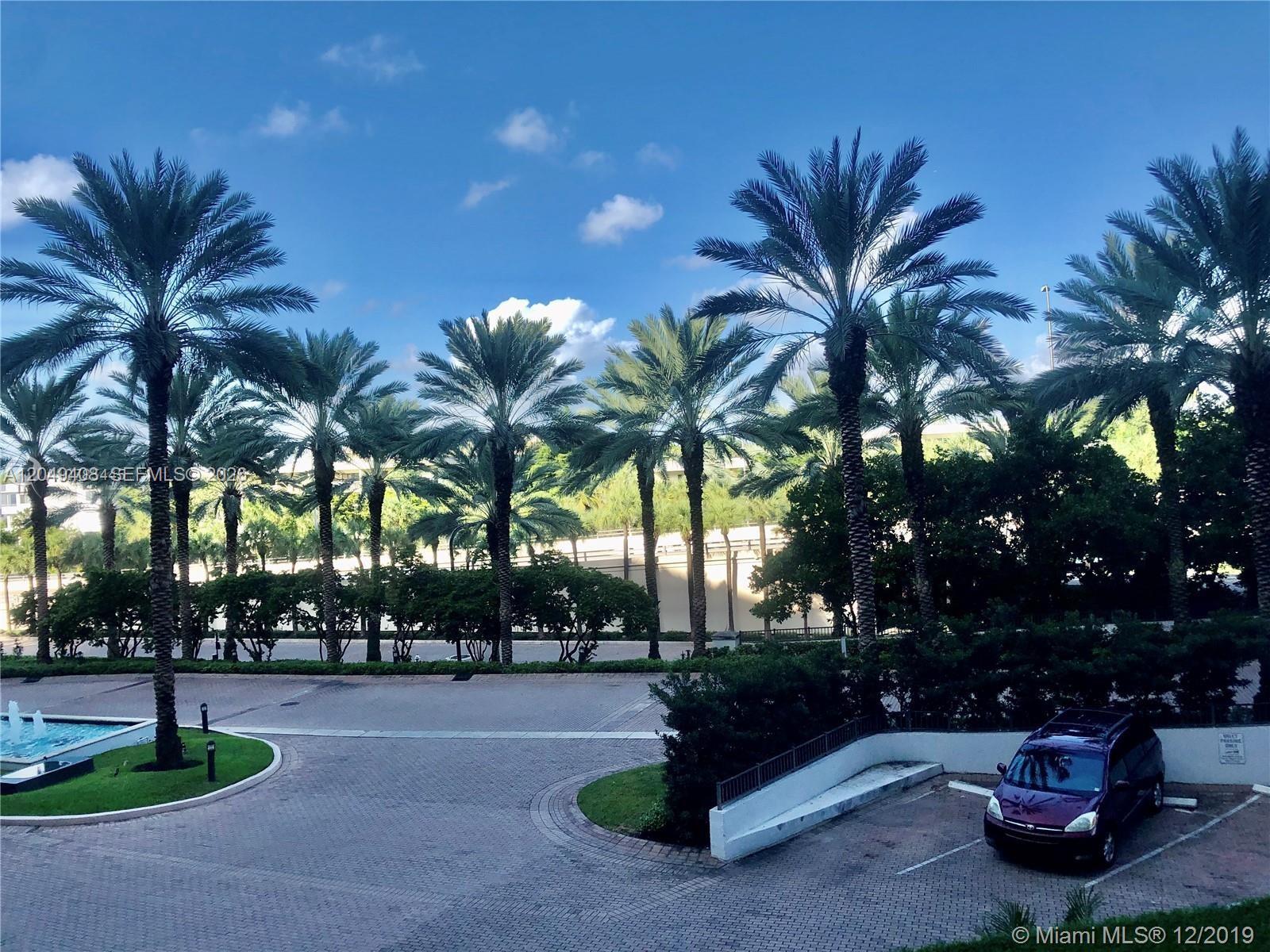 A paved driveway leads to a parking area with palm trees and a parked vehicle — 10275 Collins Ave # 230, Bal Harbour FL 33154, BAL HARBOUR, FL