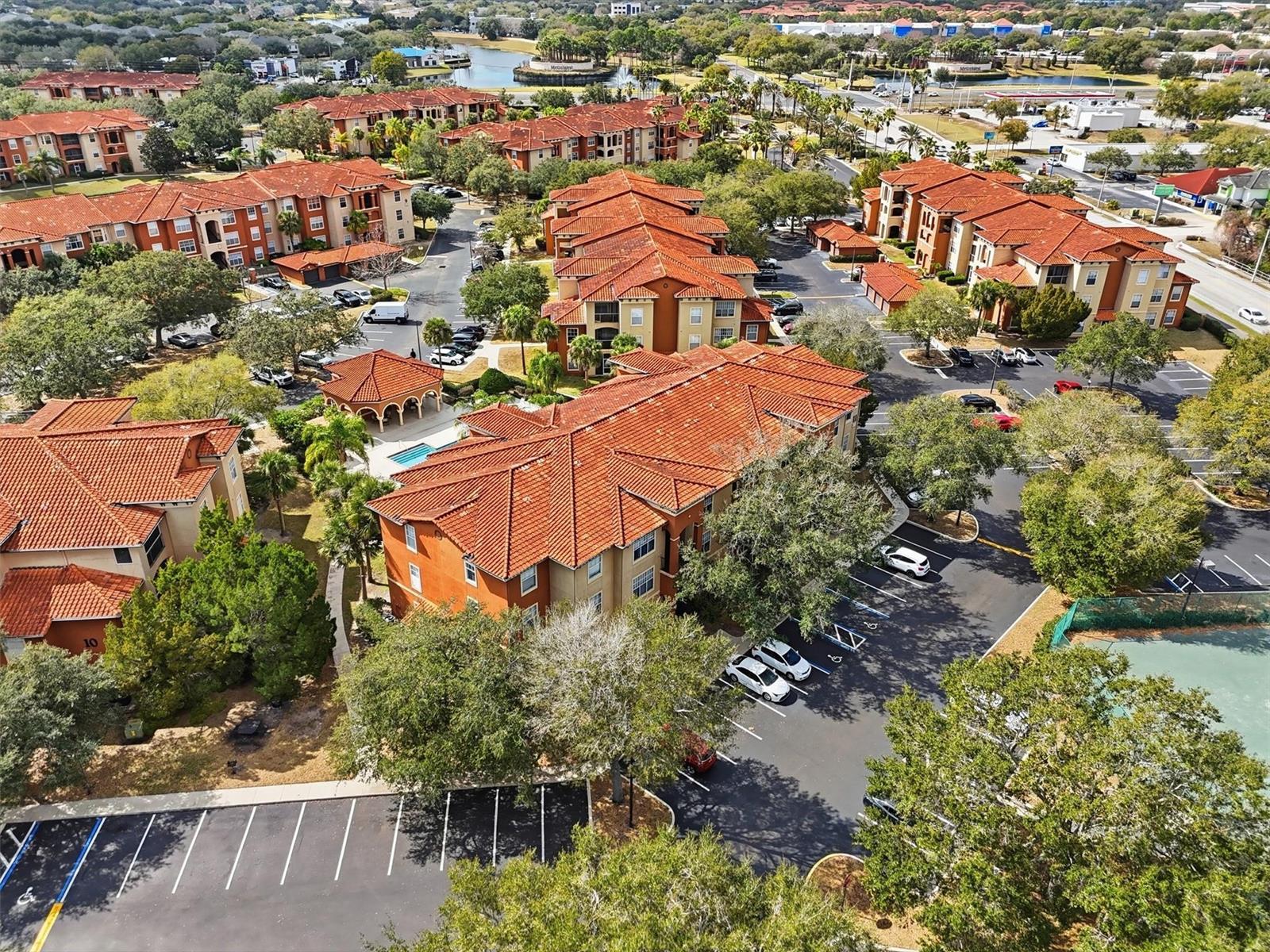 An aerial view shows multiple apartment buildings with red tile roofs and surrounding parking lots — 5518 Metrowest Boulevard # 104, Orlando FL 32811, ORLANDO, FL