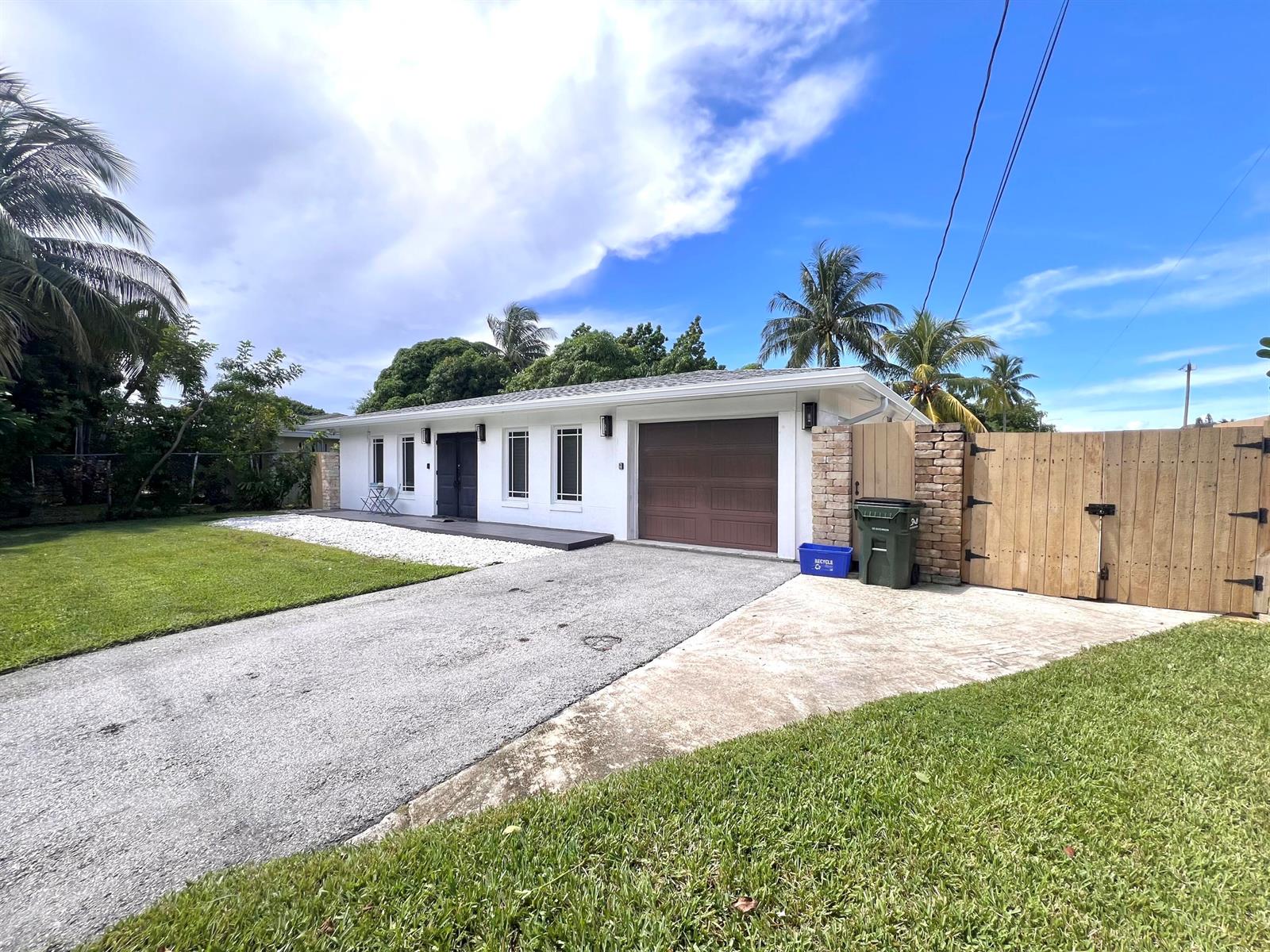 A white single-story house with a brown garage door and a wooden gate — 902 S Swinton Avenue, Delray Beach FL 33444, DELRAY BEACH, FL