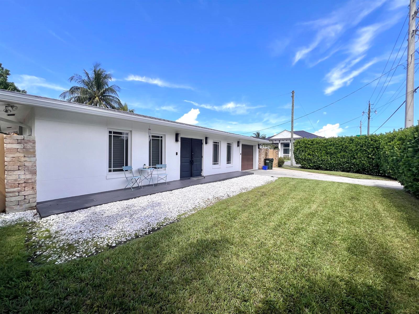A white, single-story house features a dark front door, a gravel bed, and a lawn — 902 S Swinton Avenue, Delray Beach FL 33444, DELRAY BEACH, FL