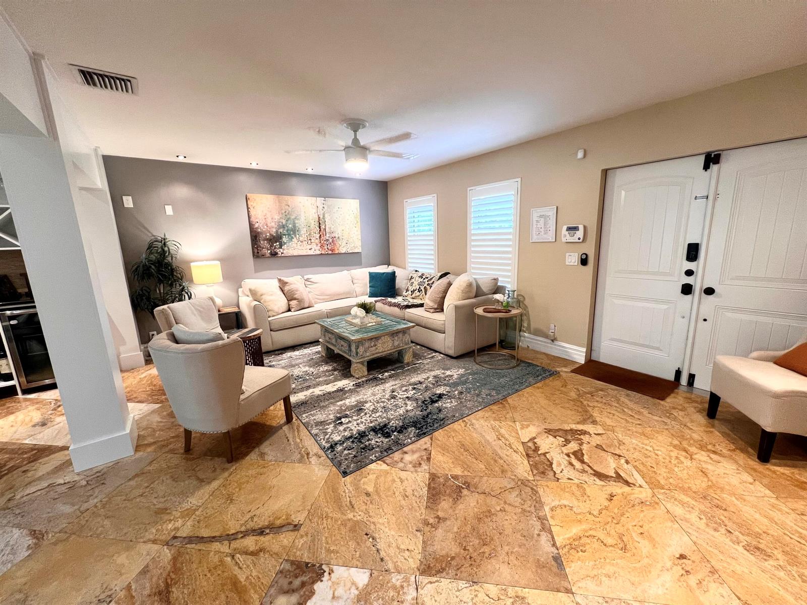 A living room features a sectional sofa, area rug, tile flooring, and a double door entrance — 902 S Swinton Avenue, Delray Beach FL 33444, DELRAY BEACH, FL