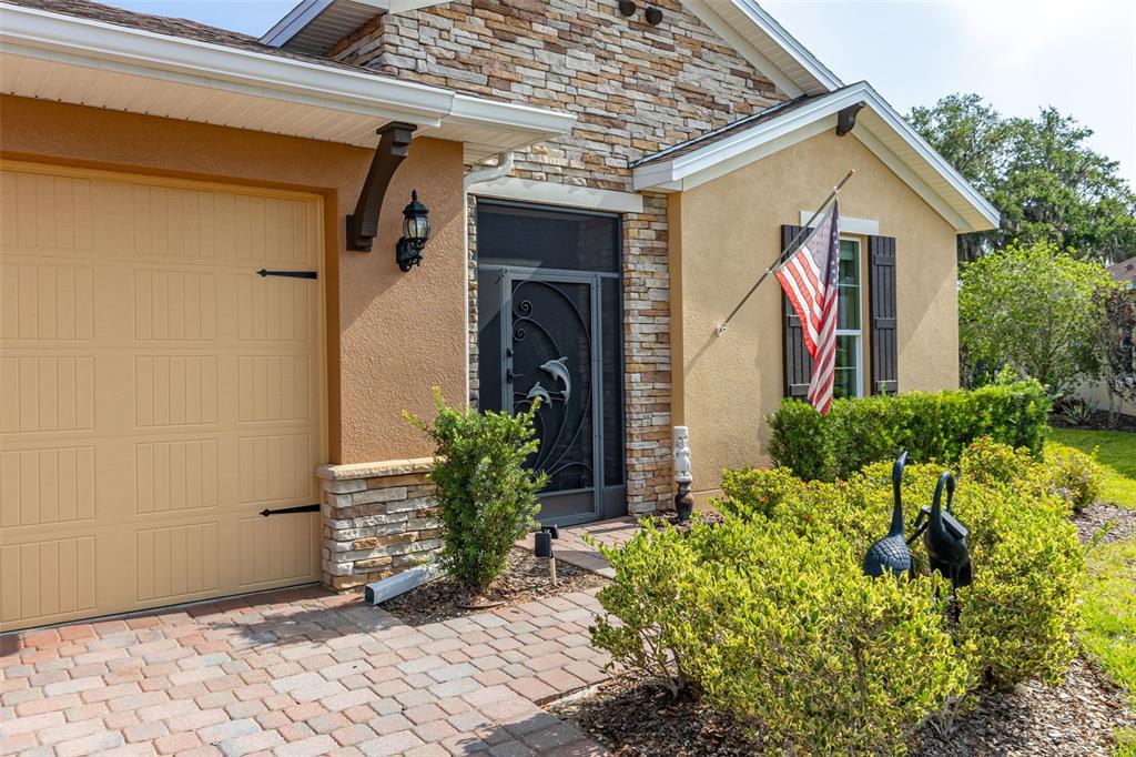The exterior of a house features a tan garage, stone accents, and a front entryway — 677 VIA CORSO COURT, KISSIMMEE, FL