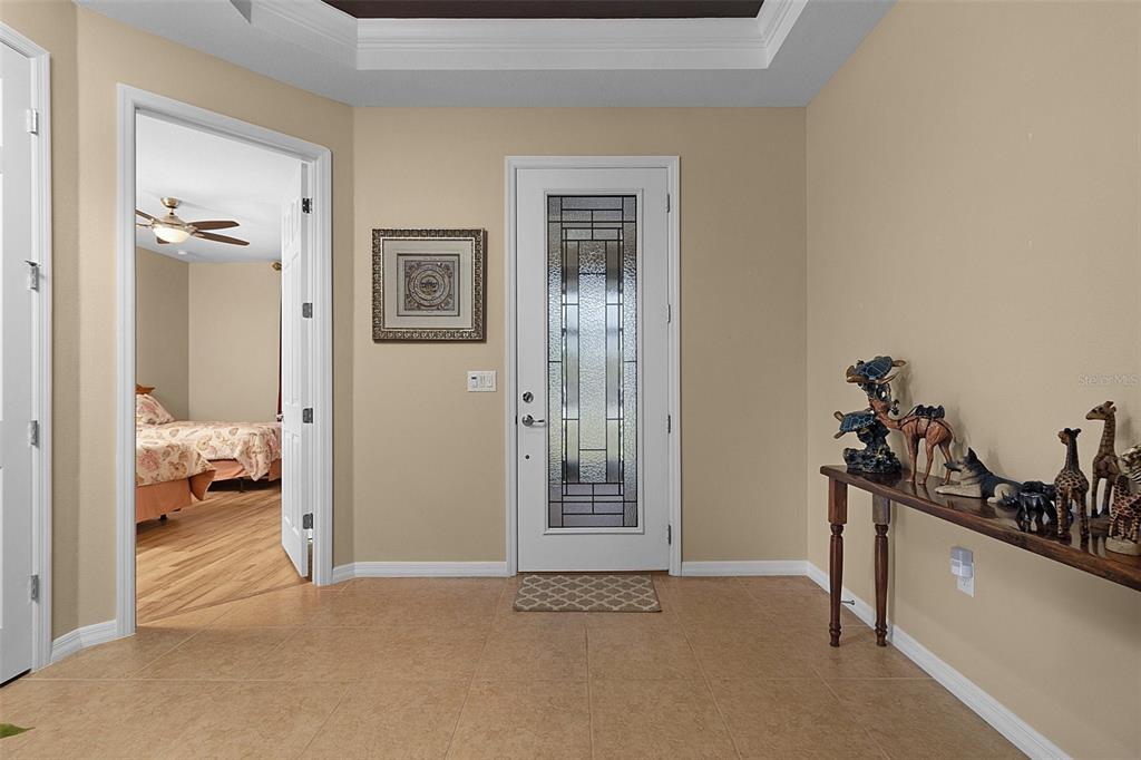 An entryway with tile flooring, a tray ceiling, and a doorway leading to a patio — 677 VIA CORSO COURT, KISSIMMEE, FL