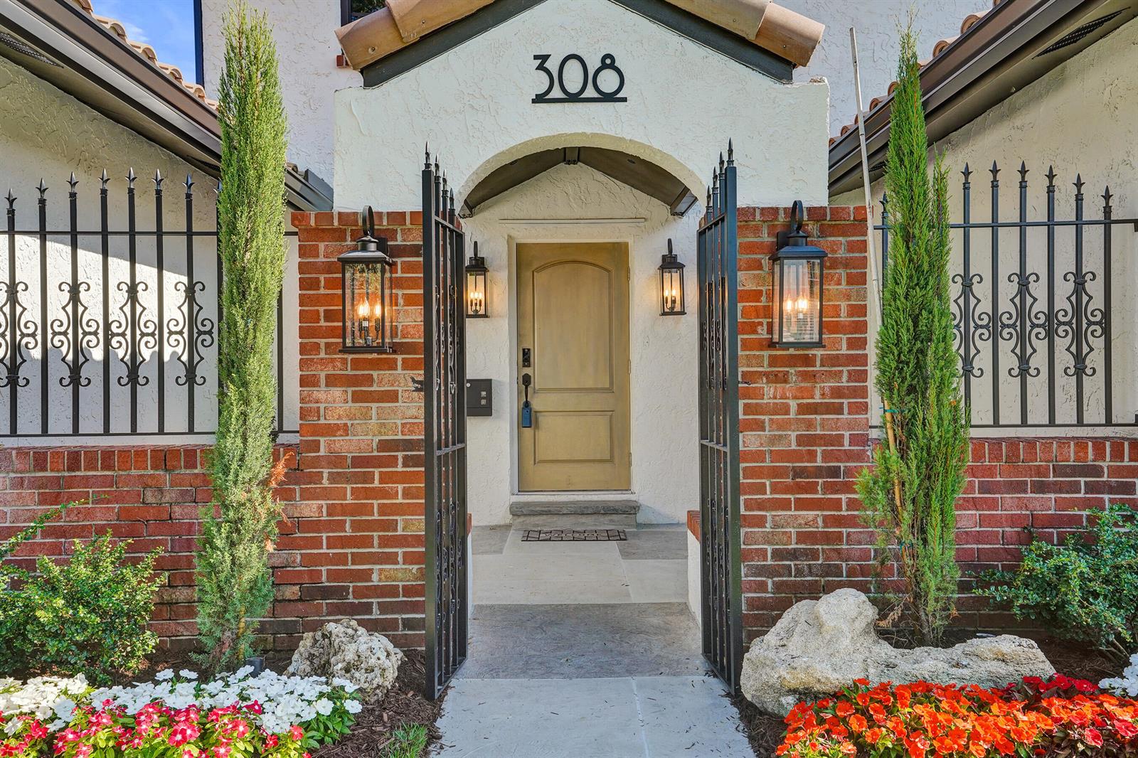 A gated brick entryway leads to a front door with a tan finish and lanterns — 308 Greymon Drive, West Palm Beach FL 33405, WEST PALM BEACH, FL