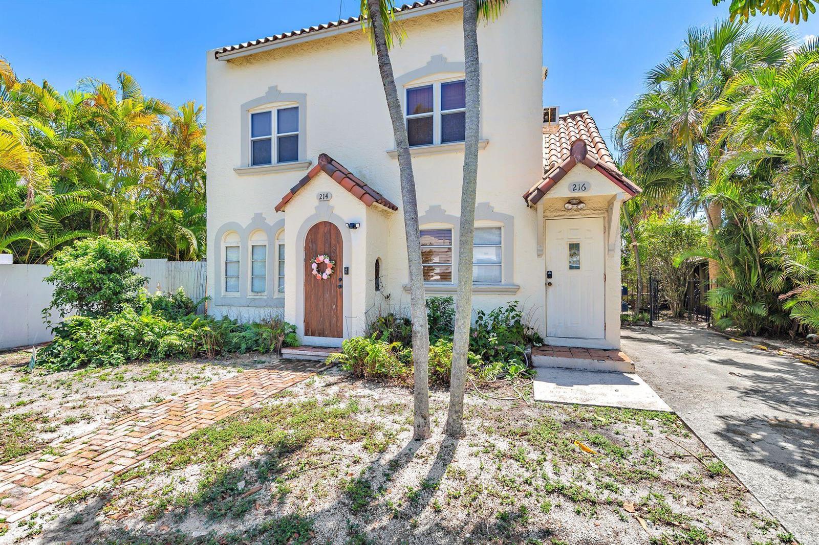 A two-story stucco duplex with two separate entrances, arched doorways, and palm trees in front — 214 Conniston Road, West Palm Beach FL 33405, WEST PALM BEACH, FL