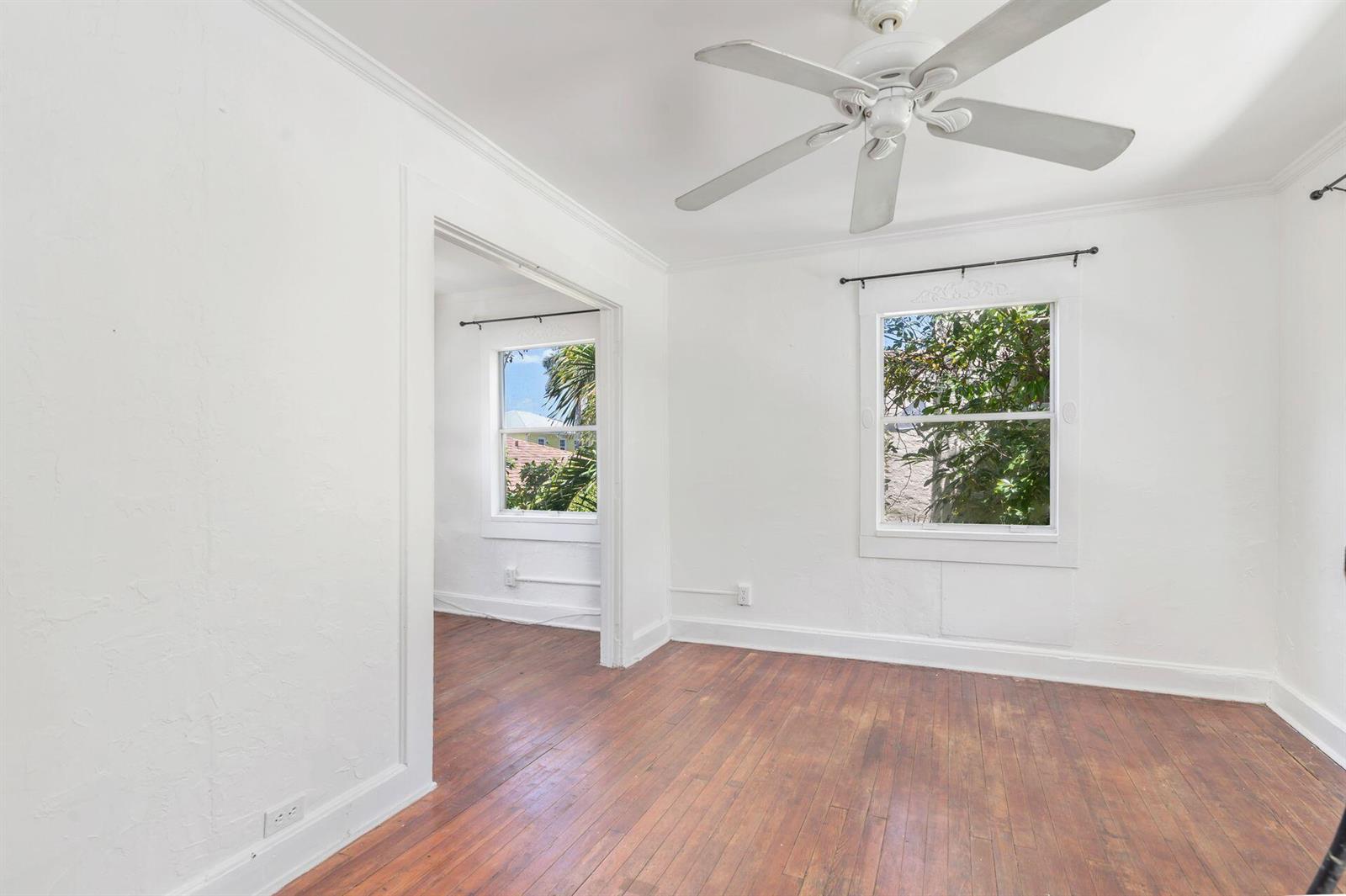 An empty room with white walls, hardwood floors, a ceiling fan, and two windows — 214 Conniston Road, West Palm Beach FL 33405, WEST PALM BEACH, FL