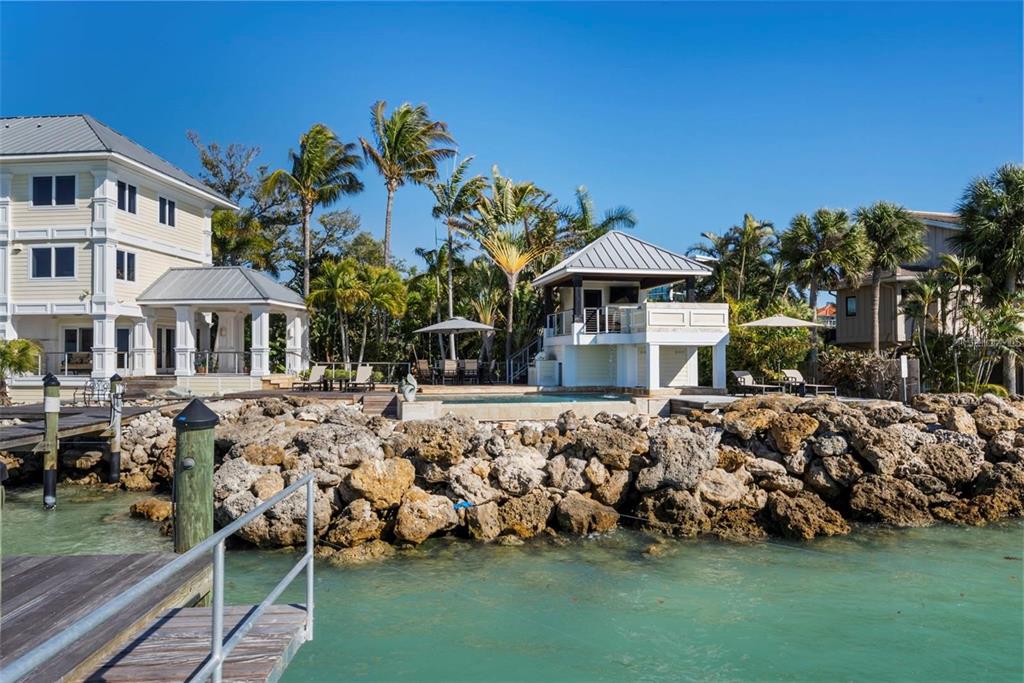 A waterfront house with a pool, a gazebo, and a rocky seawall along the shore — 3750 BAYOU LOUISE LANE, SARASOTA, FL