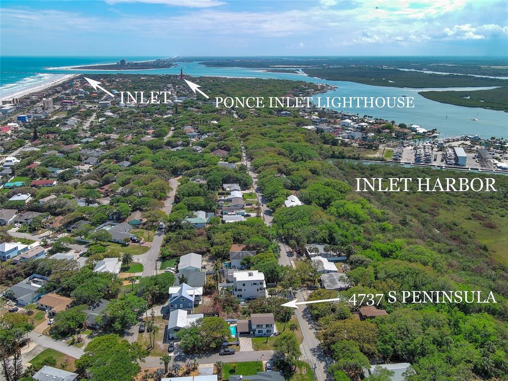 This aerial view shows a coastal residential neighborhood near an inlet, lighthouse, and harbor — 4737 S. PENINSULA DRIVE, PONCE INLET, FL