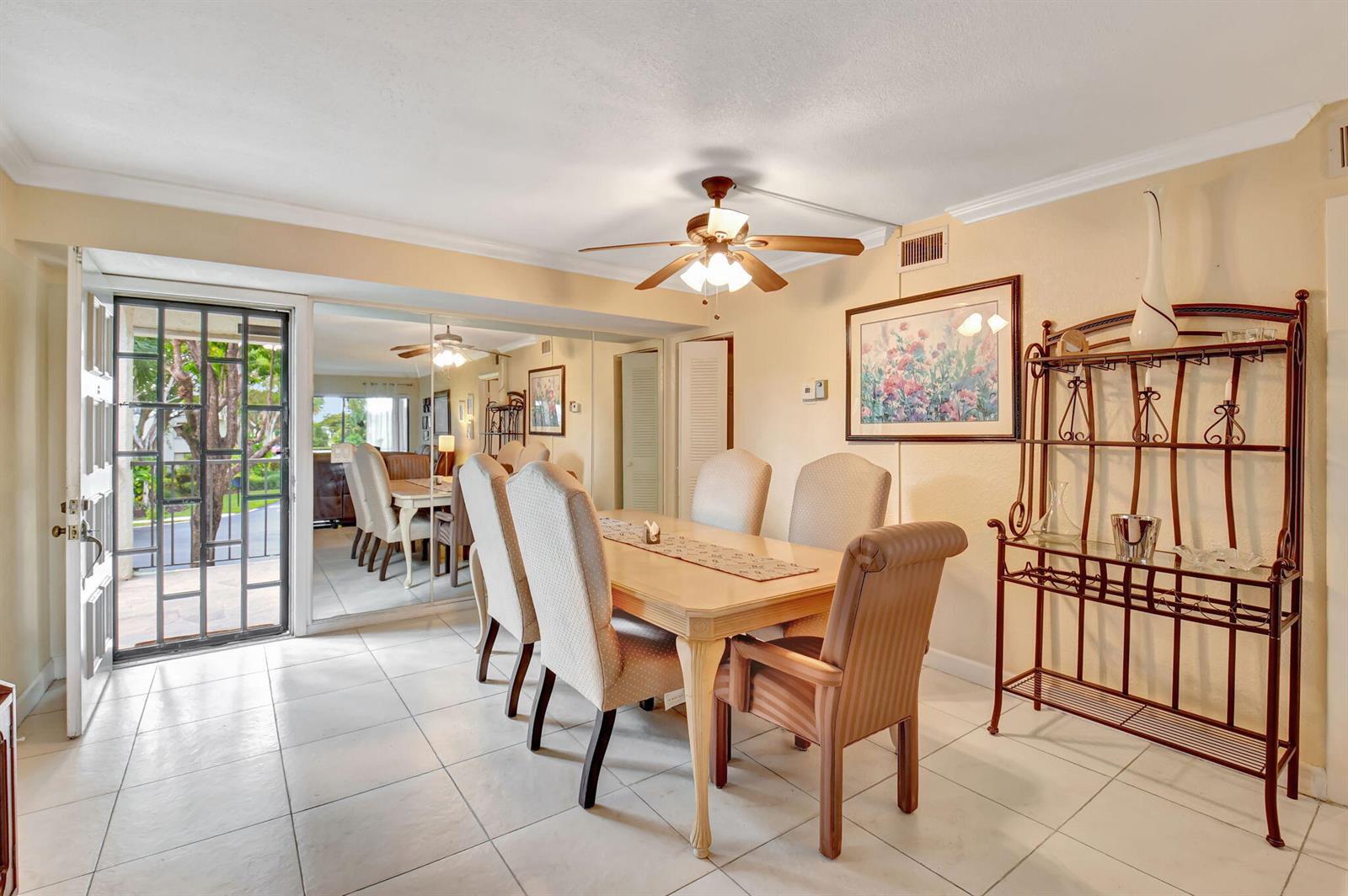 A dining room features a wooden table with six chairs, a metal baker's rack, and mirrored walls — 5715 Fairway Park Drive # 201, Boynton Beach FL 33437, BOYNTON BEACH, FL