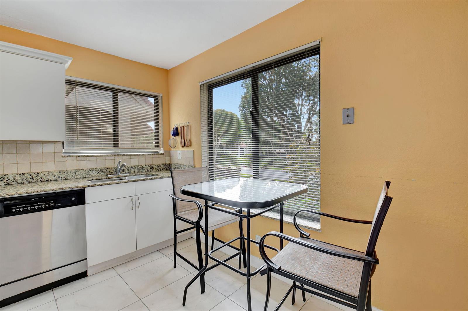 A kitchen with white cabinets, granite countertops, a small dining table, and large windows — 5715 Fairway Park Drive # 201, Boynton Beach FL 33437, BOYNTON BEACH, FL
