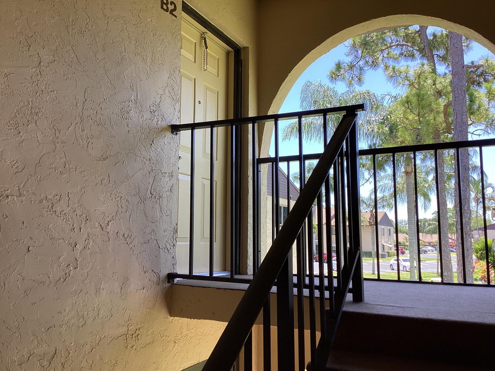 An exterior view of an apartment door labeled B2 with a black metal railing — 410 Pine Glen Lane # 2, FL 33463, FL