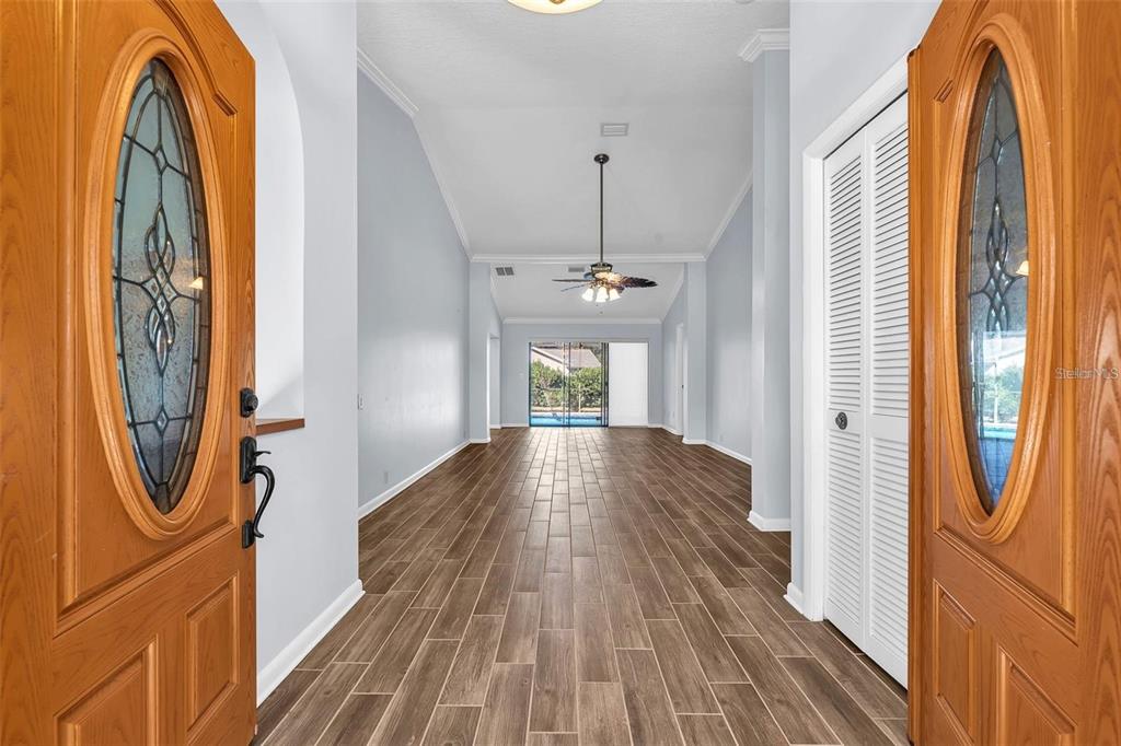 An entryway with wood-look tile flooring leads to a living area with a ceiling fan — 1702 HORSESHOE DRIVE, PLANT CITY, FL