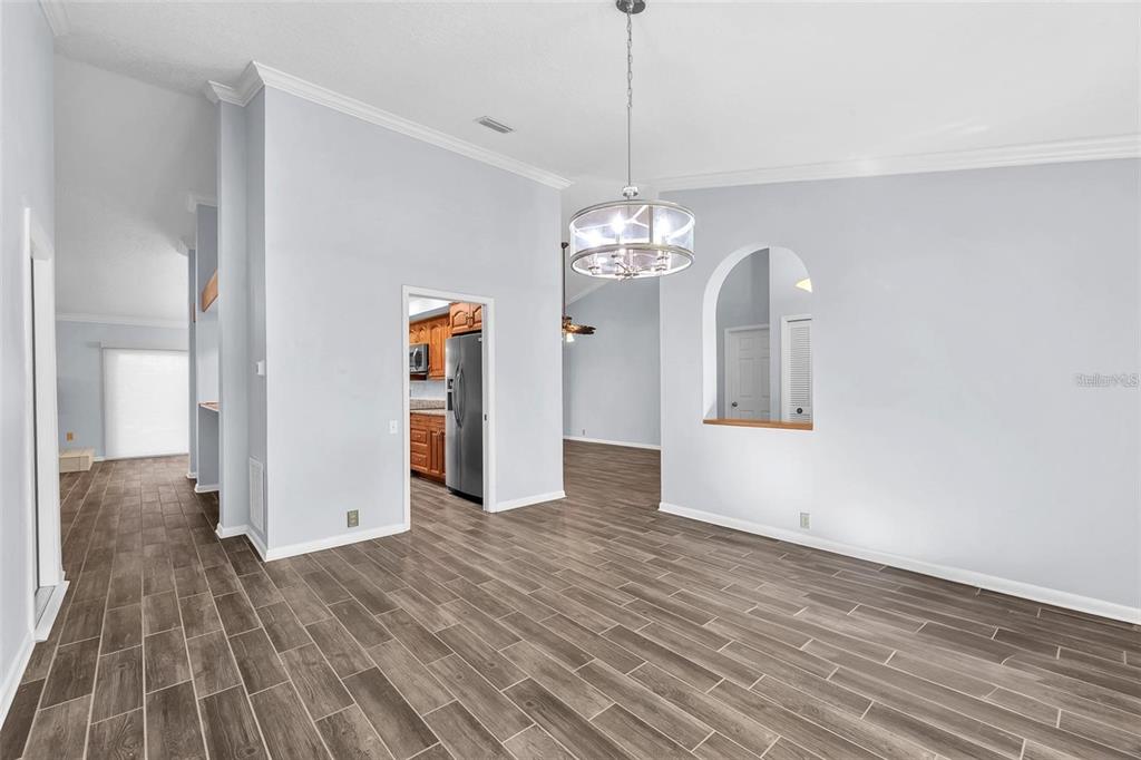 A dining area with wood-look tile flooring, a modern chandelier, and an arched wall cutout — 1702 HORSESHOE DRIVE, PLANT CITY, FL