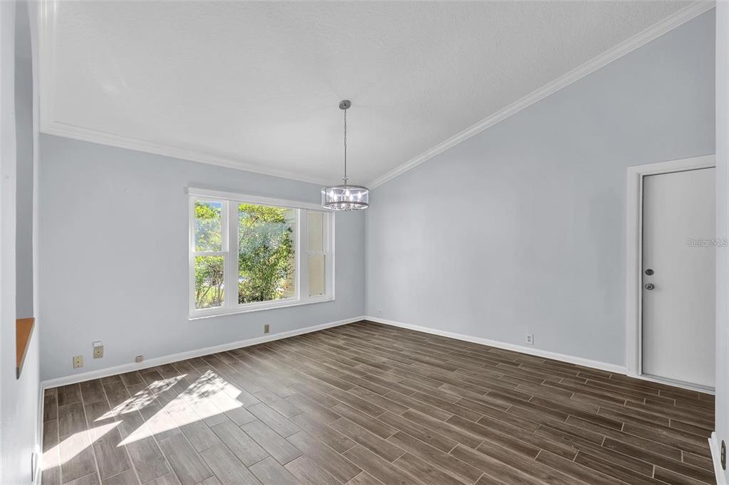 An empty dining room with light gray walls, wood-look tile flooring, and a modern chandelier — 1702 HORSESHOE DRIVE, PLANT CITY, FL