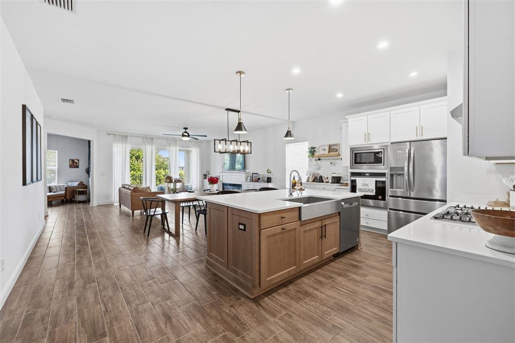 A modern open-concept kitchen and dining area with a wood-toned island and white cabinetry — 5408 TAGALONG PLACE, APOLLO BEACH, FL
