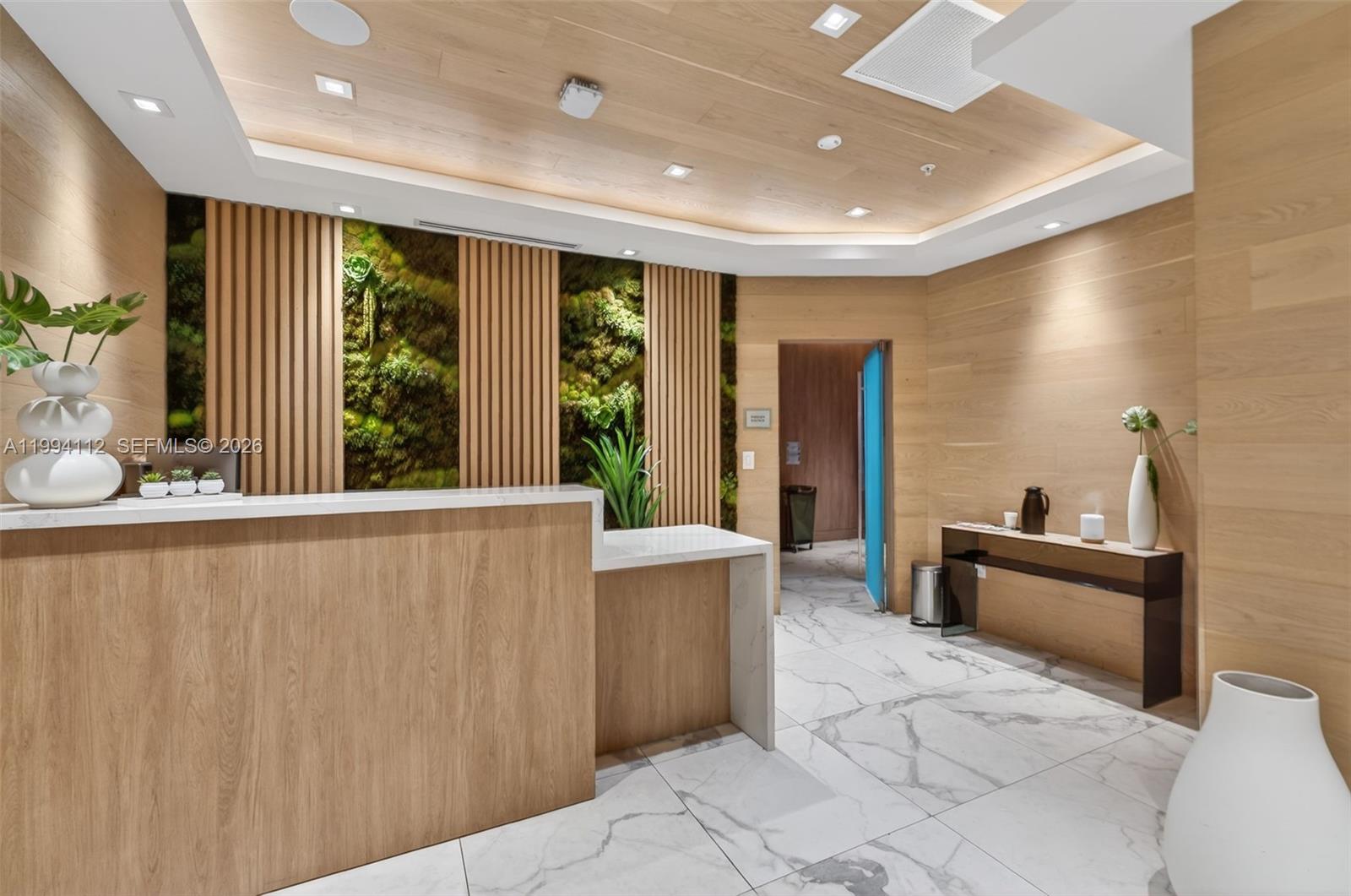 A modern reception area features a wood-paneled desk, a living plant wall, and marble flooring — 90 SW 3rd St # 1105, Miami FL 33130, MIAMI, FL