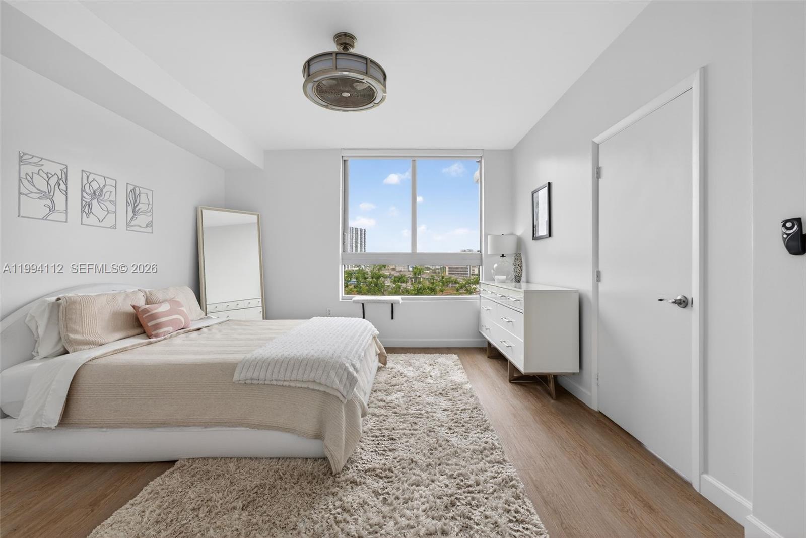 A bedroom features a bed, dresser, floor mirror, and a window with a city view — 90 SW 3rd St # 1105, Miami FL 33130, MIAMI, FL