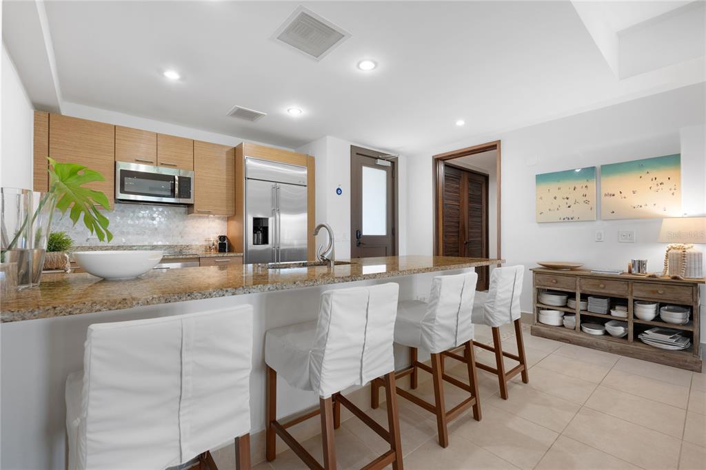 A kitchen with light wood cabinets, granite countertops, and a breakfast bar with white stools — 7000 BAHIA BEACH BLV UNIT 8268, RIO GRANDE, PR