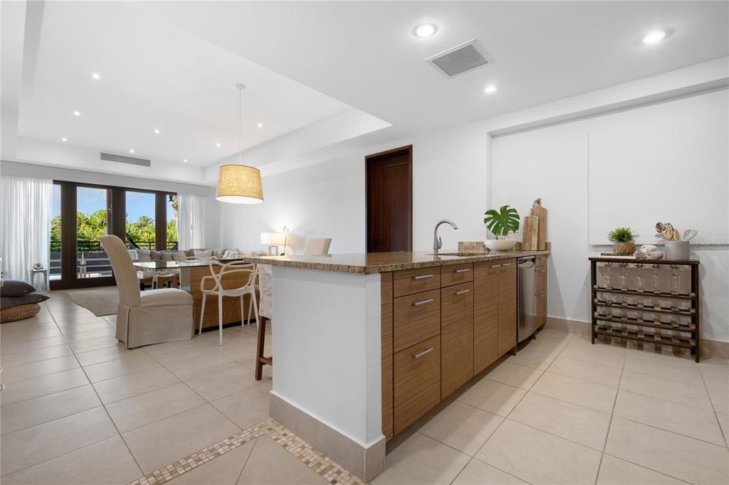 A kitchen with wood cabinets and a granite countertop opens to a dining area — 7000 BAHIA BEACH BLV UNIT 8268, RIO GRANDE, PR