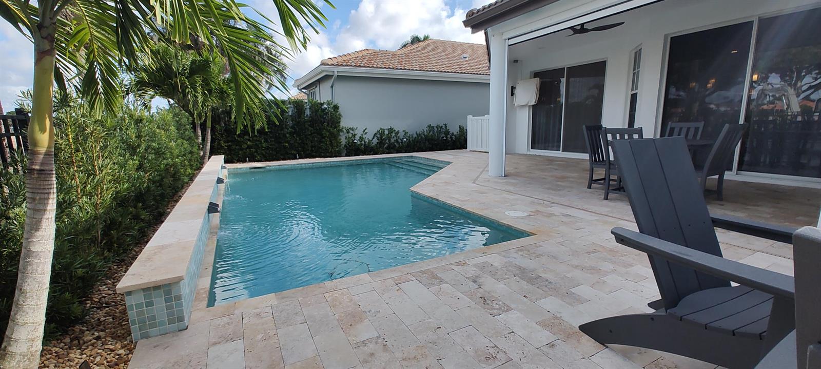 A backyard patio features a swimming pool with water features, stone pavers, and lounge chairs — 8167 Quail Meadow Way, West Palm Beach FL 33412, WEST PALM BEACH, FL