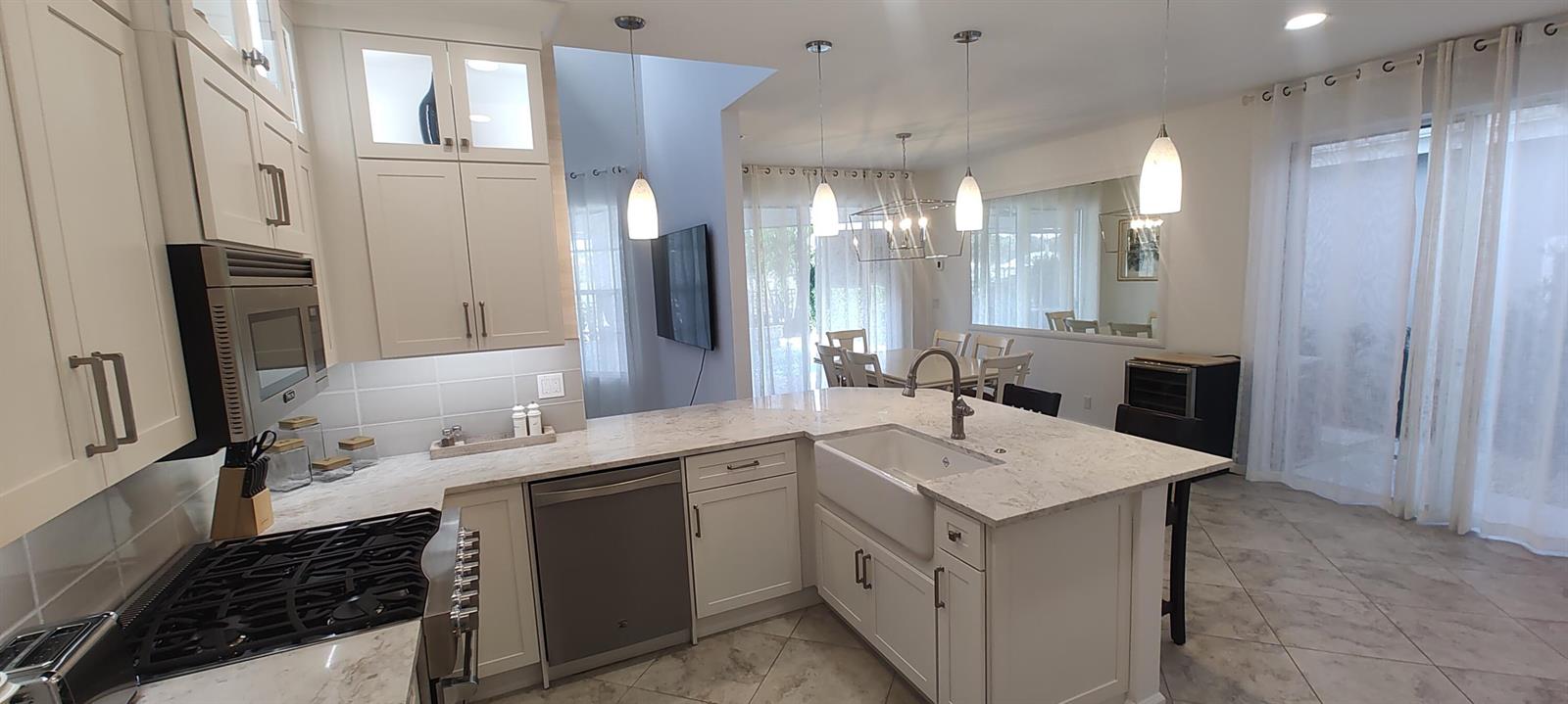 A kitchen with white cabinets, marble-look countertops, a farmhouse sink, and stainless steel appliances — 8167 Quail Meadow Way, West Palm Beach FL 33412, WEST PALM BEACH, FL