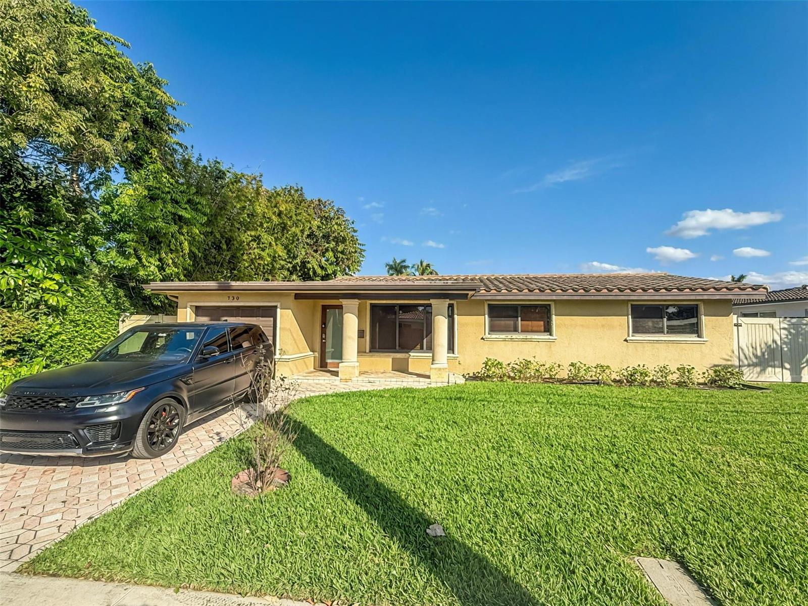 A single-story house with a yellow stucco exterior, a tiled roof, and a paved driveway — 730 SE 3rd Terrace, Pompano Beach FL 33060, POMPANO BEACH, FL