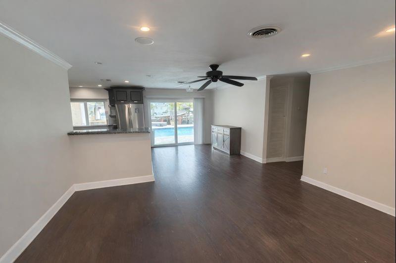 An open-concept living area with dark wood floors, a ceiling fan, and a kitchen pass-through — 730 SE 3rd Terrace, Pompano Beach FL 33060, POMPANO BEACH, FL