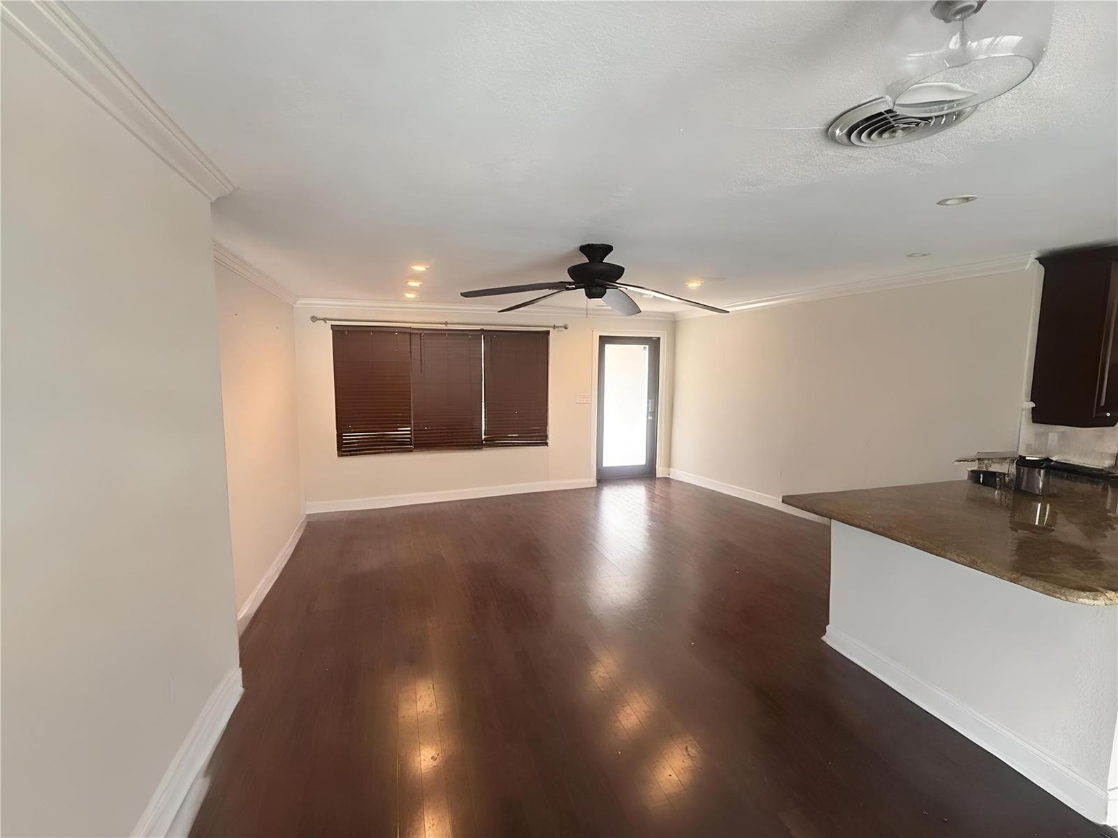 An open living area features dark hardwood floors, a ceiling fan, and a kitchen peninsula — 730 SE 3rd Terrace, Pompano Beach FL 33060, POMPANO BEACH, FL