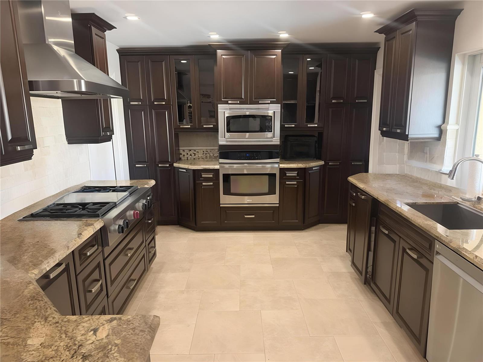A kitchen features dark wood cabinets, stainless steel appliances, and granite countertops — 730 SE 3rd Terrace, Pompano Beach FL 33060, POMPANO BEACH, FL