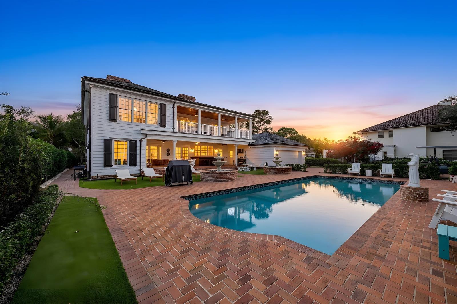 A two-story house with a pool, brick patio, and fountain at sunset — 19153 SE Jupiter River Drive, Jupiter FL 33458, JUPITER, FL