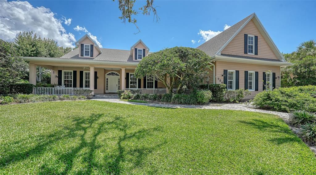 A two-story house with light-colored siding, a front porch, and a large grassy lawn — 756 VANDERBILT DRIVE, NOKOMIS, FL