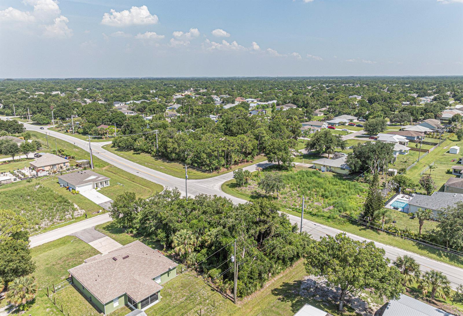 An aerial view shows a suburban neighborhood with houses, roads, and wooded areas — 8315 102nd Avenue, Vero Beach FL 32967, VERO BEACH, FL