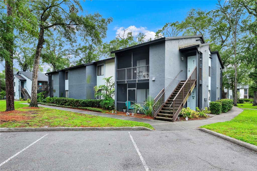 A two-story apartment building with gray stucco walls, exterior staircases, and screened-in balconies — 202 RIVERBEND DRIVE UNIT 103, ALTAMONTE SPRINGS, FL