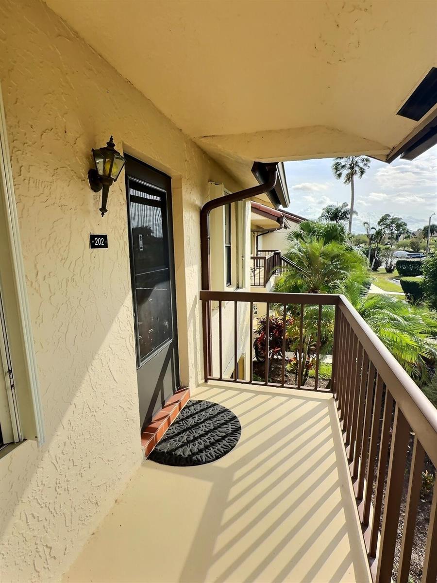 A second-floor balcony features a screen door, a wall-mounted light fixture, and a metal railing — 4682 E Lucerne Lakes Blvd Boulevard E # 202, Lake Worth FL 33467, LAKE WORTH, FL