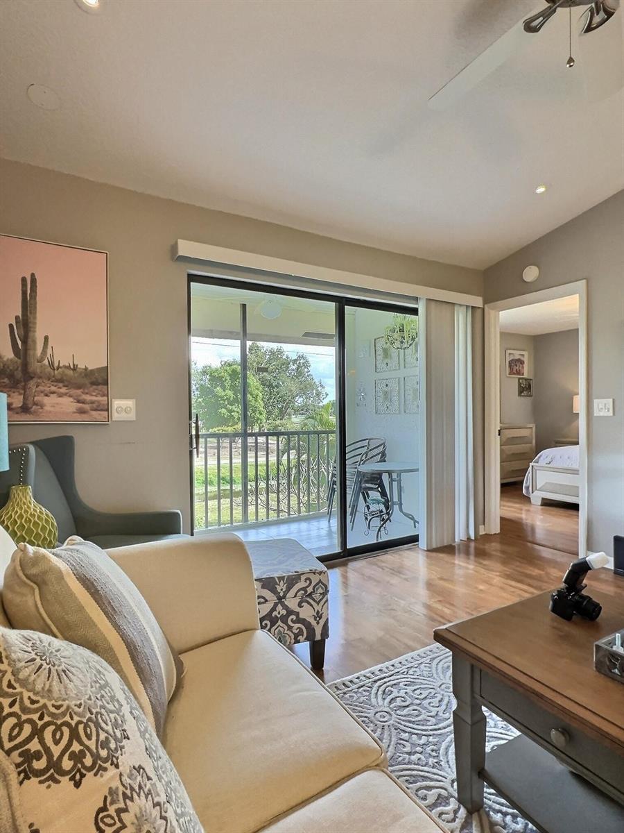A living room with a beige sofa, hardwood floors, and a sliding door to a balcony — 4682 E Lucerne Lakes Blvd Boulevard E # 202, Lake Worth FL 33467, LAKE WORTH, FL