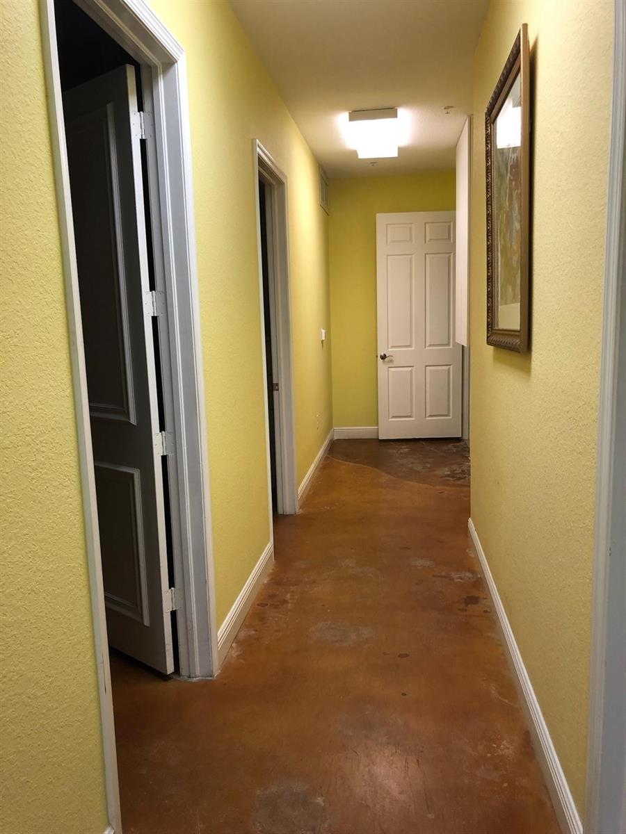 A hallway with yellow walls, a white door, and exposed concrete flooring — 6848 Griffin Road # 6, Davie FL 33314, DAVIE, FL