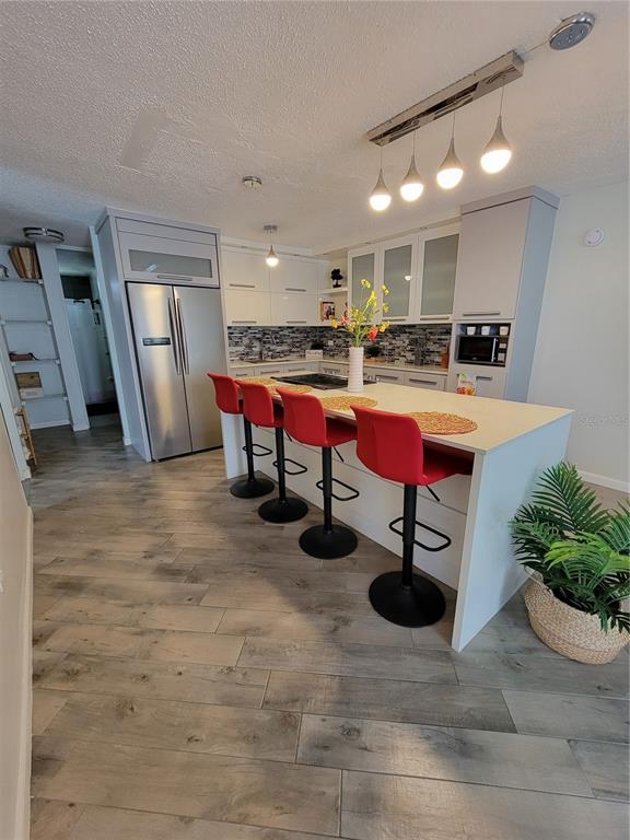 A modern kitchen features a white island with red bar stools and gray cabinetry — 7 TRINTARIAS ST., JARDINES DE DORADO DEV. UNIT C-12, DORADO, PR
