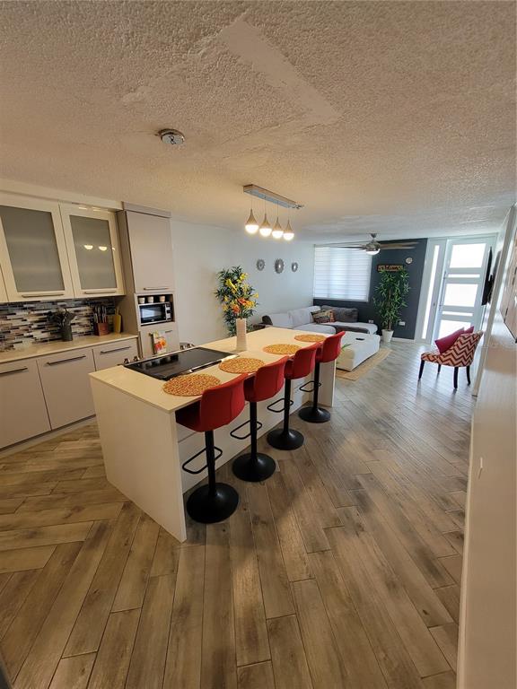 A modern kitchen with a central island and red bar stools opens into a living area — 7 TRINTARIAS ST., JARDINES DE DORADO DEV. UNIT C-12, DORADO, PR