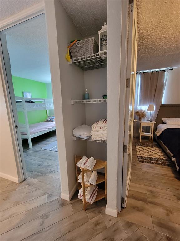 A narrow open shelving unit sits between two bedrooms with wood-look tile flooring — 7 TRINTARIAS ST., JARDINES DE DORADO DEV. UNIT C-12, DORADO, PR