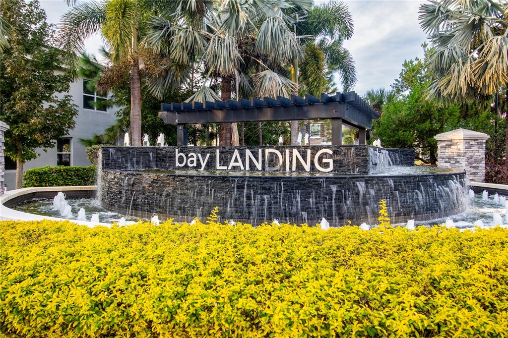 A tiered stone fountain with a pergola sits behind a bed of yellow shrubs — 2801 MIDNIGHT PEARL DRIVE, SARASOTA, FL