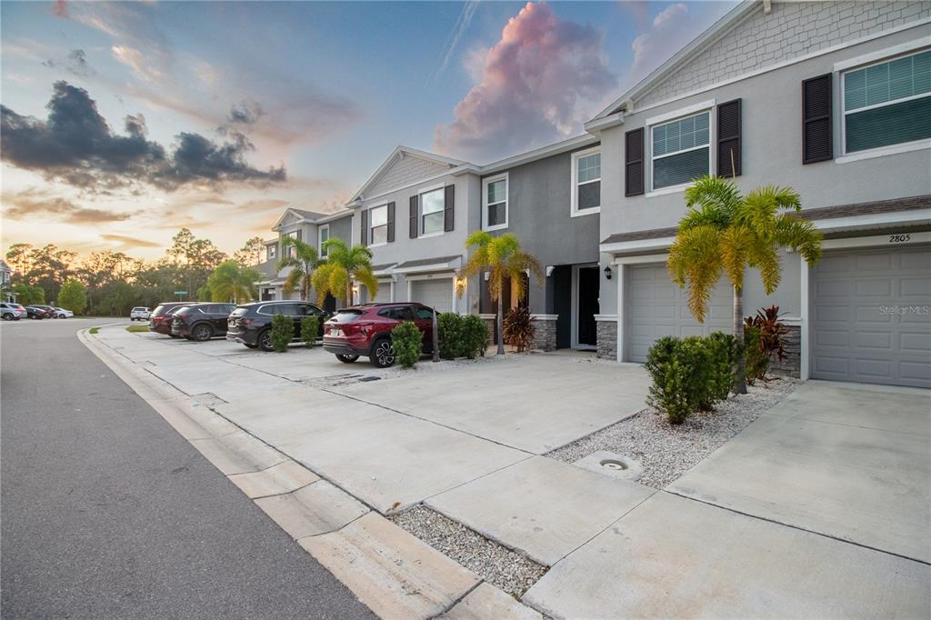 A row of two-story townhouses with gray siding, attached garages, and palm trees in front — 2801 MIDNIGHT PEARL DRIVE, SARASOTA, FL