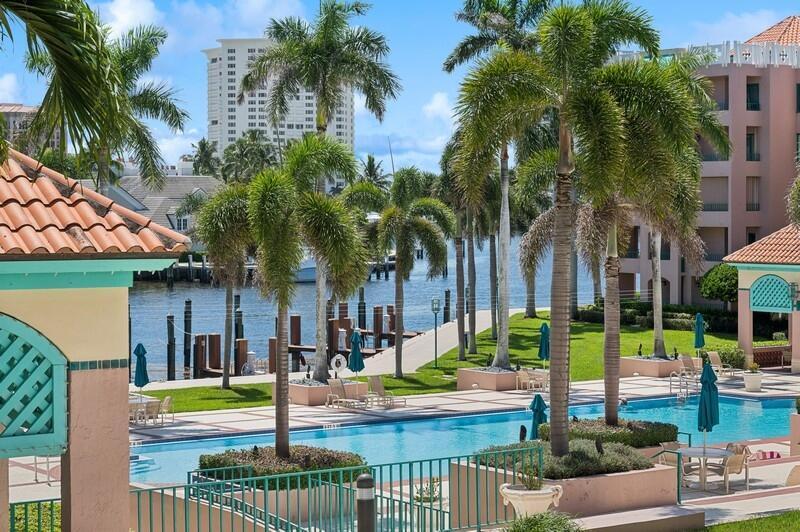 A swimming pool sits on a patio surrounded by palm trees and waterfront buildings — 120 SE 5th Avenue # 326, Boca Raton FL 33432, BOCA RATON, FL