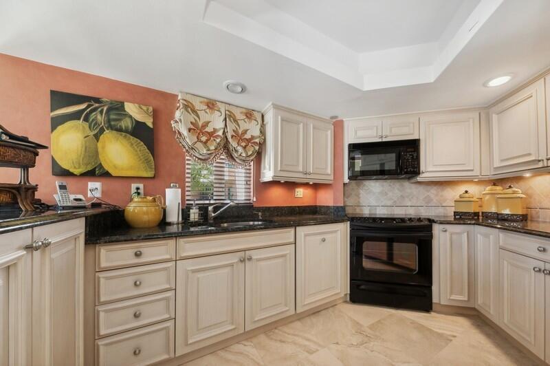 A kitchen with cream cabinets, dark granite countertops, a black oven, and peach-colored walls — 120 SE 5th Avenue # 326, Boca Raton FL 33432, BOCA RATON, FL