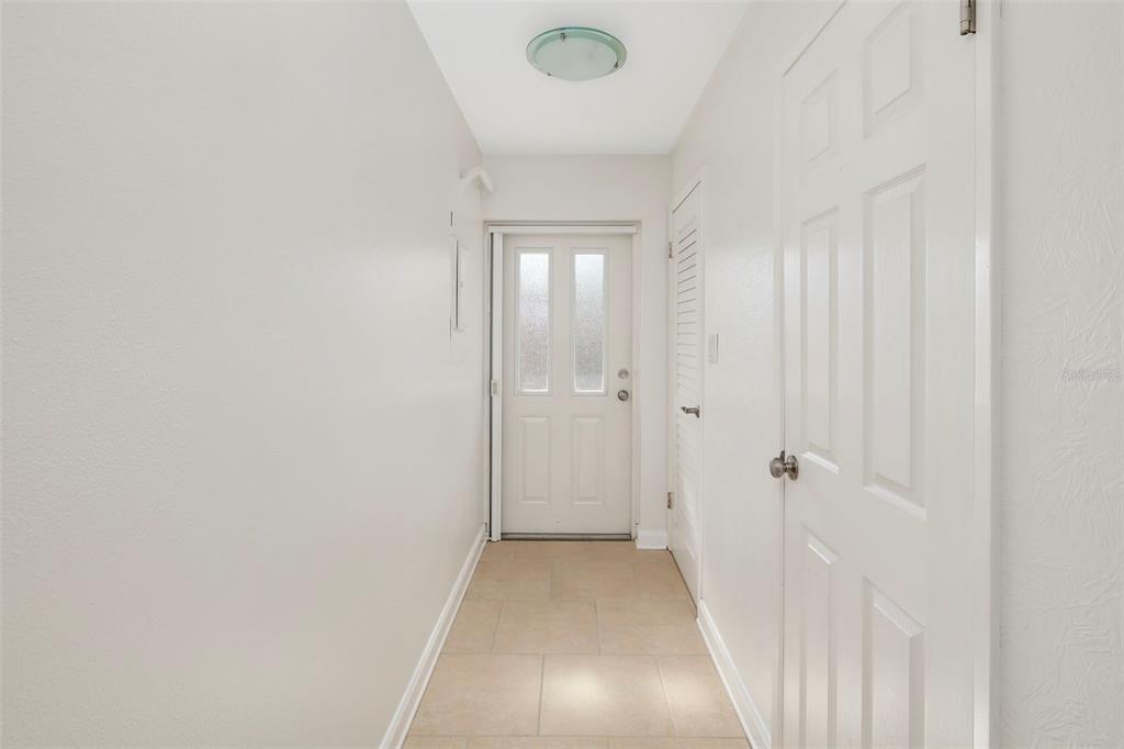 A bright entryway features light-colored tile flooring, white walls, and a white front door — 2155 WOOD STREET UNIT A14, SARASOTA, FL