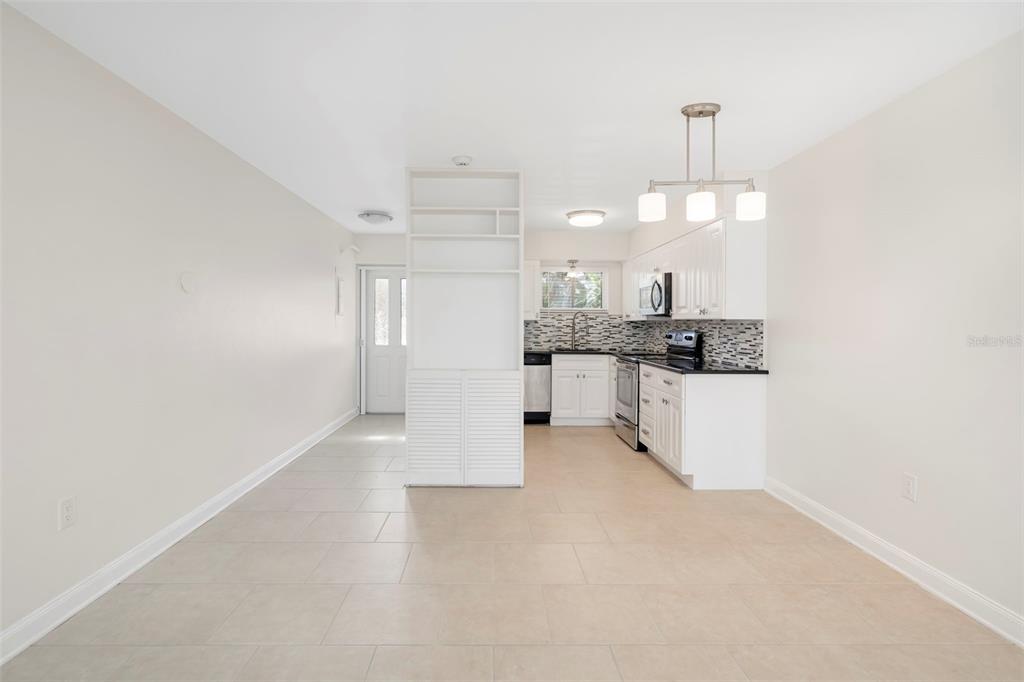 An open-concept kitchen and dining area features white cabinets, tile flooring, and a room divider — 2155 WOOD STREET UNIT A14, SARASOTA, FL