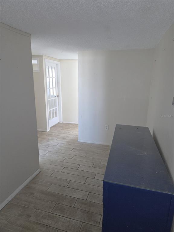 A hallway with light wood-look tile flooring leads toward a white French door — 7212 GULF HIGHLANDS DRIVE, PORT RICHEY, FL